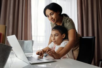 a person and a child looking at a laptop